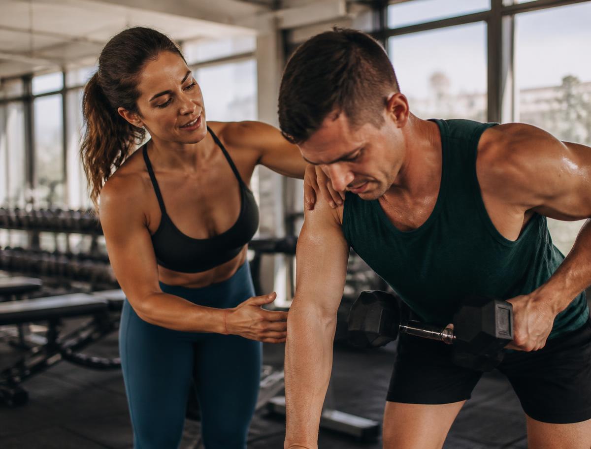 Personal trainer coaching a client in a bright modern gym