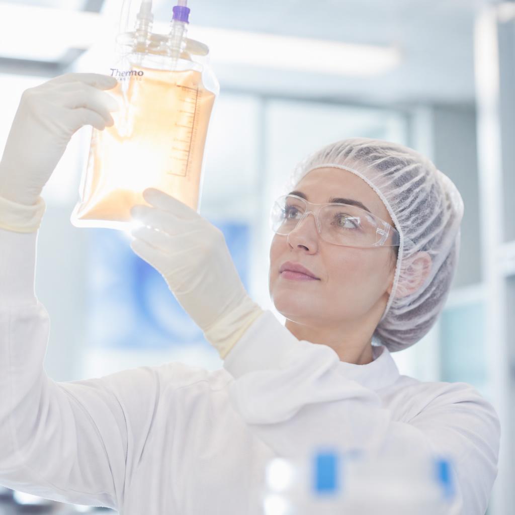 Technician working at a biosafety cabinet in a cell therapy manufacturing cleanroom