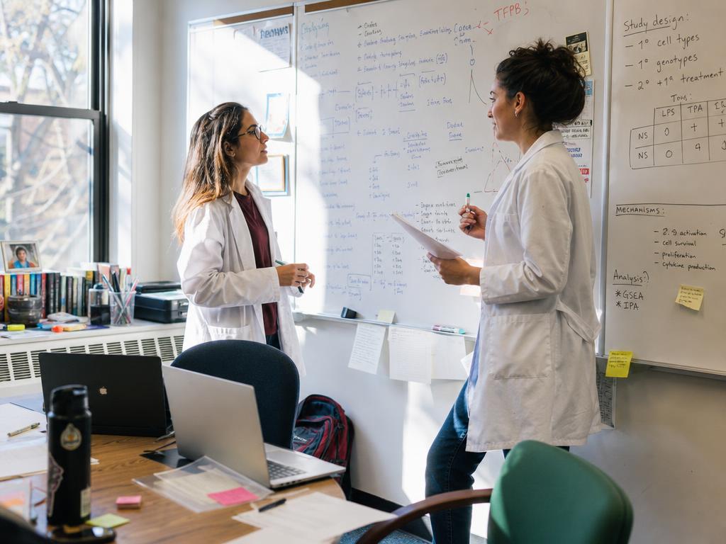Researchers reviewing genomic data beside a microscope in a university laboratory